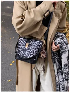 Detail der trendigen Leoparden-Beuteltasche mit goldenem Drehverschluss und Plüsch-Anhänger