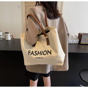 Primer plano de un bolso tote de lona con asas de cuero marrón y texto Fashion Paris