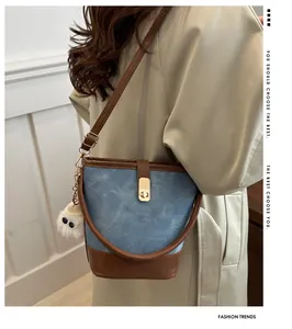 Detalle de bolso bucket retro con cierre dorado y colgante de felpa en gabardina beige
