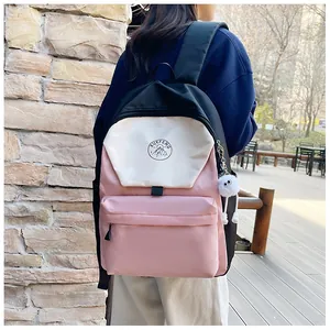 Primer plano de mochila de nailon tricolor con colgante de felpa y logotipo frontal