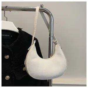 Detail of white tweed crescent bag with silver metallic zipper on black jacket backdrop