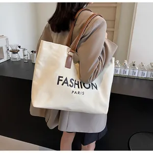 Detalle de bolsa tote de lona con correas de cuero marrón y texto Fashion Paris