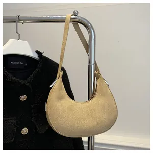 Detail view of khaki suede crescent bag with silver buckles hanging on a rack