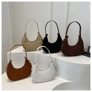 Close-up of five suede crescent bags in beige, black, red, brown, and white colors