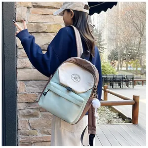 Vista lateral de mochila estética con bloques de color y pompón blanco exterior