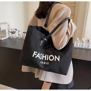Primer plano del bolso tote de lona negra con texto Fashion Paris y asas de cuero