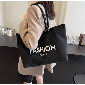 Detalle de un bolso tote de lona negra con estampado Fashion Paris y asas delgadas