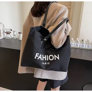 Detalle del bolso tote grande de lona negra con estampado Fashion Paris y asas de cuero