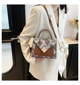 Detail of snake skin pattern handbag with brown leather flap and square hardware