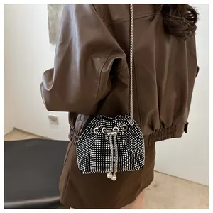 Détail du sac seau en strass argentés avec bandoulière chaîne et cordon perle sur veste