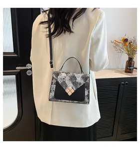 Detail of snake pattern stitching and decorative buckle on a chic crossbody bag