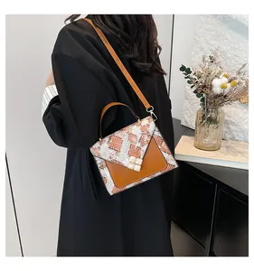 Detail of snake print leather handbag with decorative square buckles and adjustable strap