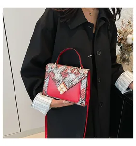 Detail of elegant red faux-leather bag with snakeskin pattern and floral gold clasp