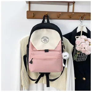 Detalle de mochila escolar tricolor con colgante de peluche en gancho de madera