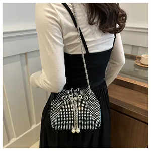 Détail d'un sac seau noir chic orné de strass argentés et de cordons en perles blanches