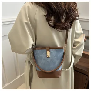 Bolso cubo de moda en denim y cuero con cierre de metal llevado por una modelo