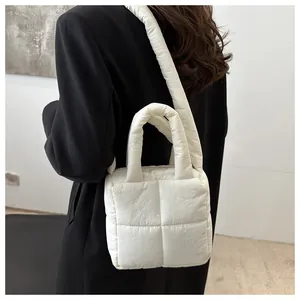 Detalle de bolso acolchado blanco con asa acolchada y correa ajustable para hombro
