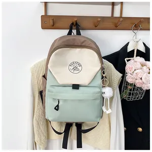 Mochila de nailon patchwork tricolor con logo de montaña y pompón blanco decorativo