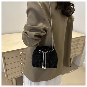Détail d'un sac seau noir en strass avec chaîne argentée et cordon en perles sur modèle