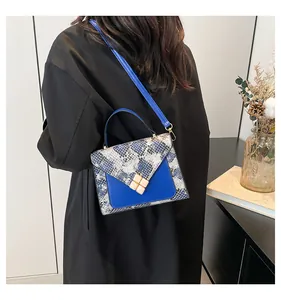 Detail view of the snakeskin pattern and golden flower buckle on the blue handbag