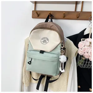 Detalle de mochila escolar tricolor con logo de montaña y colgante de peluche