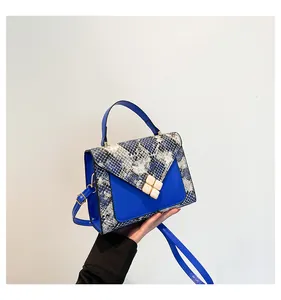 Close-up of royal blue leather shoulder bag with faux snakeskin texture and gold buckle