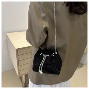Détail du sac seau noir en strass avec chaîne argentée et cordons ornés de perles blanches