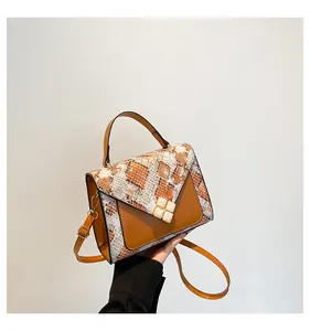 Detail of snake skin texture and white square buckle on a brown leather handbag