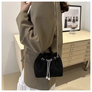 Détail du sac seau noir à cordon avec strass et breloques en perles porté par un mannequin