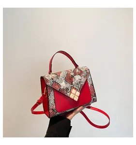 Close-up of red leather crossbody bag with snake skin pattern and gold clover buckle