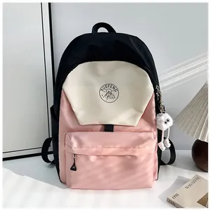 Detalle de mochila escolar de nailon tricolor con llavero de ojos de peluche y logo