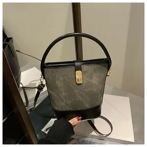 Detalle del cierre de metal dorado y adornos de cuero negro en el bolso cubo