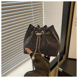 Détail d'un sac seau noir avec strass argentés, perles et une bandoulière en chaîne