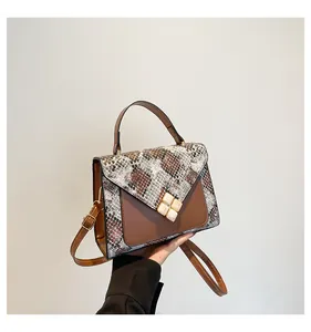 Detail of a brown leather crossbody bag with snake print and clover emblem