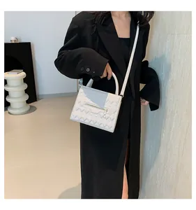 Borsa a tracolla bianca quadrata trapuntata geometrica indossata su cappotto nero