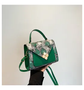 Macro view of green leather bag with snake print flap and floral buckle detailing