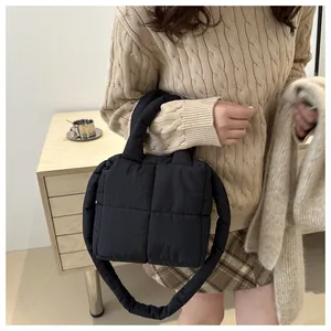 Detalle de bolso acolchado negro con textura de nube suave y correa de hombro a juego
