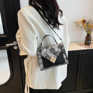 Chic monochrome snake pattern patchwork handbag with a gold clover clasp and top handle