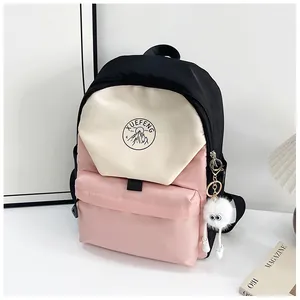 Detalle de la mochila tricolor con diseño de retazos, logotipo redondo y colgante de felpa