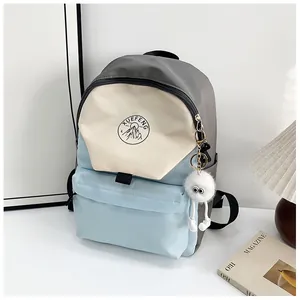 Detalle de mochila de bloques de colores con logo de montaña y colgante de peluche