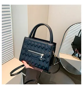 Dettaglio di borsa nera trapuntata con cerniera e manico rotondo dallo stile elegante