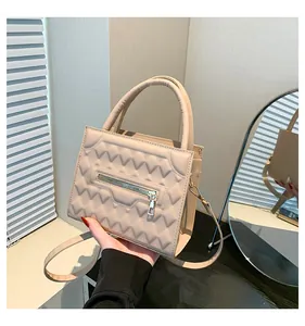 Dettaglio borsa quadrata beige con trama trapuntata a V e cerniera dorata lucida