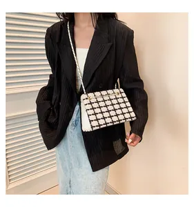 Detailed view of the black and white tweed crossbody bag with golden chain strap on model