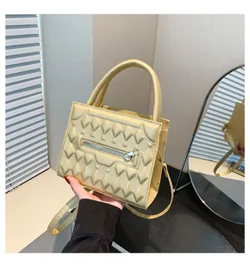 Dettaglio borsa quadrata color oro champagne con trama geometrica e hardware argento