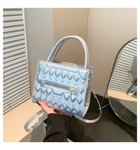 Dettaglio della borsa a tracolla argento goffrata con cerniere metalliche e doppi manici
