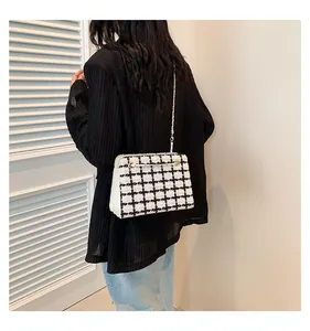 Detail of small black and white tweed shoulder bag with gold chain strap on model