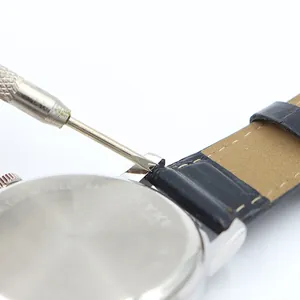 Dual-head spring bar tool removing a leather watch strap from a stainless steel case