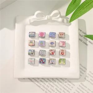 Detail of 16 Italian charms with floral and eye motifs in a white ceramic dish