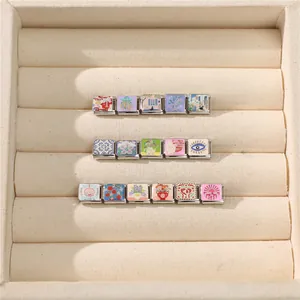 Detailed view of Italian charm links with floral, shell and evil eye enamel patterns