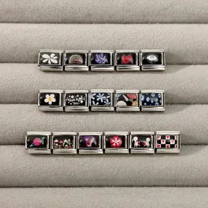 Macro view of Italian charm links with daisy, evil eye, and heart designs in a jewelry box